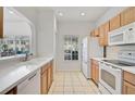 A functional kitchen featuring white appliances, tile floors, and wood cabinets at 233 Cape Harbour Loop # 107, Bradenton, FL 34212