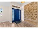Bright entryway with a statement blue door, custom wall art, and wood-look flooring at 2424 Affinity Ln, North Port, FL 34286