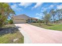 Single-story home with an attached garage, mature landscaping, and a long concrete driveway at 2618 Titania Rd, Englewood, FL 34224