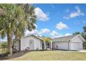 Charming single-story home featuring lush lawn, palm trees, and a two-car garage, showcasing curb appeal at 27416 Natal Dr, Punta Gorda, FL 33983