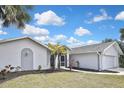 Charming single-story home featuring lush lawn, palm trees, and a two-car garage, showcasing curb appeal at 27416 Natal Dr, Punta Gorda, FL 33983