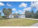 Charming single-story home featuring lush lawn, palm trees, and a two-car garage, showcasing curb appeal at 27416 Natal Dr, Punta Gorda, FL 33983