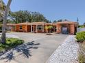 Exterior of a one-story home featuring a metal roof, an attached garage, and manicured landscaping at 409 Armada S Rd, Venice, FL 34285