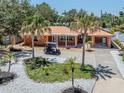 Exterior of a one-story home with a metal roof, mature landscaping, a long driveway, and an electric golf cart at 409 Armada S Rd, Venice, FL 34285