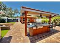 Outdoor kitchen with bar seating, built-in grill, custom lighting, and brick pavers offer backyard entertaining at 409 Armada S Rd, Venice, FL 34285