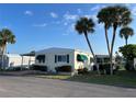 Inviting mobile home exterior with mature palm trees and covered parking at 417 Via Veneto, Venice, FL 34285