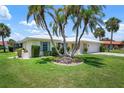 Single story home with 2 car garage featuring lush landscaping, mature palms, and a circular garden at 465 Laurencin Dr, Nokomis, FL 34275