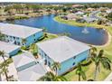 Stunning aerial view of blue condos nestled beside a serene lake with a central fountain at 5739 Sabal Trace Dr # 102, North Port, FL 34287