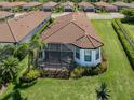 An aerial view of the home's rear exterior and screened-in lanai, with lush landscaping and mature palm trees at 5853 Semolino St, Nokomis, FL 34275