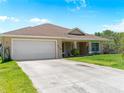 Tan home with a two-car garage and a well-manicured lawn, with an ample driveway for parking at 6199 Stamp St, Port Charlotte, FL 33981