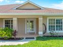 Covered front porch with double glass doors, columns, and manicured landscaping at 6199 Stamp St, Port Charlotte, FL 33981