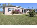 A view of a single-story home with a well-kept lawn, landscaping, and a front patio at 6231 Jordan St, North Port, FL 34287