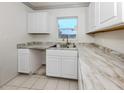 Bright kitchen featuring marble-look countertops, stainless steel sink, and white cabinets with a view from the window at 6231 Jordan St, North Port, FL 34287