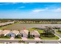 A high-angle view showcasing the house and the surrounding homes, lake, and greenery in the neighborhood at 629 Ibiza Loop, Venice, FL 34292