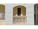 Close-up of a balcony with stone balusters and an arched entryway to the front door at 63 Palm Dr, Placida, FL 33946