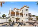 Charming three-story home with multiple balconies, white pillars, and a garage at 63 Palm Dr, Placida, FL 33946