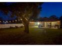 Backyard view at dusk with string lights highlighting a patio, dining area, and a fire pit at 6497 Honeycomb Cir, North Port, FL 34291