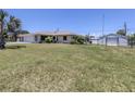 Lawn view of the house and fenced in yard, surrounded by green grass and trees at 976 Euclid Rd, Venice, FL 34293