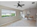 Bright living room featuring tile flooring, large windows, and a ceiling fan at 1104 Auburn Cove Cir, Venice, FL 34292
