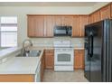 Kitchen featuring light wood cabinets, stainless sink, white appliances, and black refrigerator at 11649 Tempest Harbor Loop, Venice, FL 34292