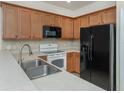 Kitchen with stainless steel sink, light wood cabinets, white countertops, and black microwave and refrigerator at 11649 Tempest Harbor Loop, Venice, FL 34292
