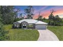 Beautiful home with a metal roof, manicured lawn, and a long driveway leading to a two-car garage at 1214 Rumson Ct, North Port, FL 34288