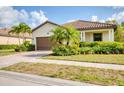 Charming single-story home with a well-manicured lawn, mature landscaping, and a brown tile roof at 12370 Canavese Ln, Venice, FL 34293
