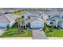 Stunning aerial view of a modern home with manicured landscaping and a brick driveway, situated near a serene lake at 12816 Morning Mist Pl, Venice, FL 34293