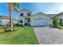 Charming two-story home featuring a paved driveway, well-manicured lawn, and a bright orange front door at 12816 Morning Mist Pl, Venice, FL 34293