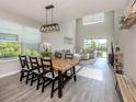 Open-concept dining area with large windows, modern lighting fixture and tile floors overlooking the living room at 15364 Isla Palma Ln, Nokomis, FL 34275