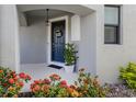 Inviting front entrance featuring a dark blue door with a wreath, potted plants, and vibrant red flowers at 15364 Isla Palma Ln, Nokomis, FL 34275