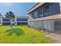 Condo rear exterior showcasing an enclosed lanai with screen windows and manicured lawn at 1728 S Lakeside Dr # 1720B, Venice, FL 34293