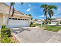 Large driveway leading to a two-car garage with mature landscaping and a walkway at 1799 Fountain View Cir, Venice, FL 34292
