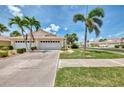 Inviting one-story home with a two-car garage, driveway, and manicured lawn with palm trees at 1799 Fountain View Cir, Venice, FL 34292