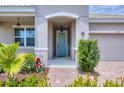 Inviting entryway featuring a light blue front door, decorative plants, and brick paver walkway at 2034 Mesic Hammock Way, Venice, FL 34292