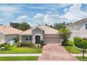 Beautiful home showcasing a clay tile roof, brick paver driveway, and lush front yard landscaping at 2034 Mesic Hammock Way, Venice, FL 34292