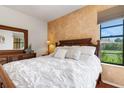 Cozy main bedroom with white bedding, a wooden dresser, and a window with green landscape views at 2104 Batello Dr, Venice, FL 34292