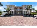 Gorgeous two-story home showcasing a balcony, white columns, a brick driveway, and well-manicured landscaping at 2322 Bayshore Rd, Nokomis, FL 34275