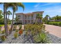 Beautifully landscaped front yard with colorful flowers, mature palm trees, and a circular paver driveway at 2322 Bayshore Rd, Nokomis, FL 34275
