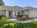 Close-up of the home's front yard featuring flowerbed landscaping and the front door at 304 Rosewood Ct, Venice, FL 34293