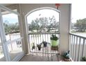 Balcony view with potted plants, metal railing, and lush green trees at 320 Clearbrook Cir # 203, Venice, FL 34292