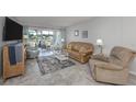 Cozy living room with neutral paint, tile floors, comfortable seating, and sliding glass doors to a lanai at 418 Cerromar Ct # 158, Venice, FL 34293