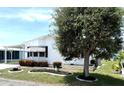 Quaint single-story home with white siding, lush landscaping, and a large tree in the front yard at 453 Sharks Pt, North Port, FL 34287