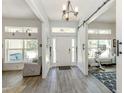 Bright foyer with wood-look tile flooring, a modern chandelier, and a sliding barn door at 460 Bard Rd, Venice, FL 34293