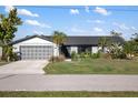Well-maintained single-story home featuring lush front yard landscaping and a two-car garage at 5140 Administration St, Port Charlotte, FL 33948