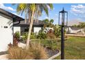Well-manicured front yard with lush landscaping, palm trees, decorative rock, and a contemporary lamppost at 5140 Administration St, Port Charlotte, FL 33948