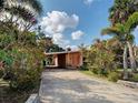 Concrete driveway leads to a covered carport and front entrance, surrounded by lush landscaping at 602 Bonito Ave, Nokomis, FL 34275