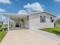 Home showcasing attached carport, a well-maintained lawn, mature palm trees, and comfortable front yard at 700 Blackburn Blvd, North Port, FL 34287