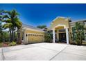 Charming yellow house boasting a wide driveway, two-car garage, and tropical landscaping at 8209 Snowy Egret Pl, Bradenton, FL 34202