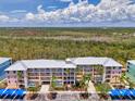 Multi-level condo building featuring colorful facade, covered parking, and tropical landscaping against a scenic natural backdrop at 8409 Placida Rd # 206, Placida, FL 33946